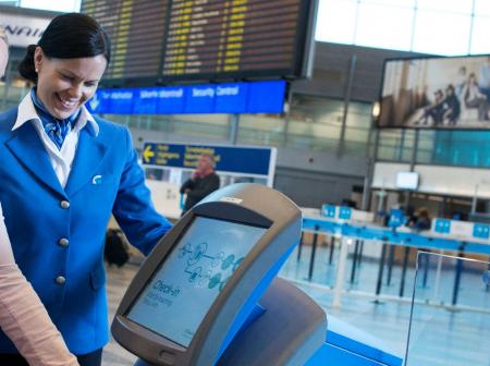 Nainen käyttää lähtöselvitysautomaattia lentokentällä.