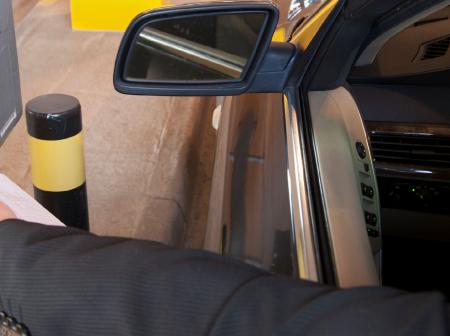 A person placing receipt into scanner to open boom barrier.