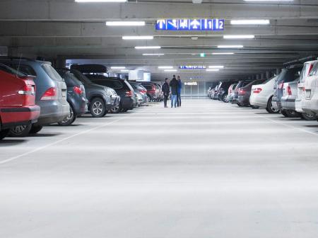 Autoja pysäköitynä valaistussa parkkihallissa.