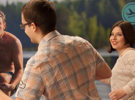 A man and a woman in front of a big poster.