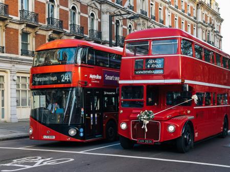 Two double decker busses stopped at street light in London.