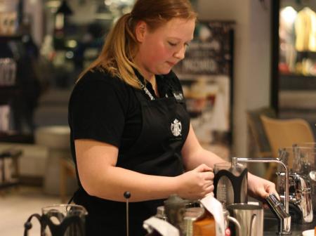 A woman making a coffee drink.