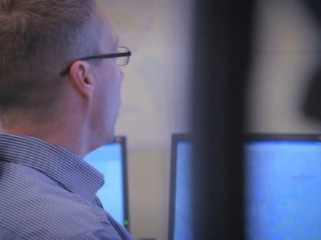 Air traffic controller working, surrounded by monitors.