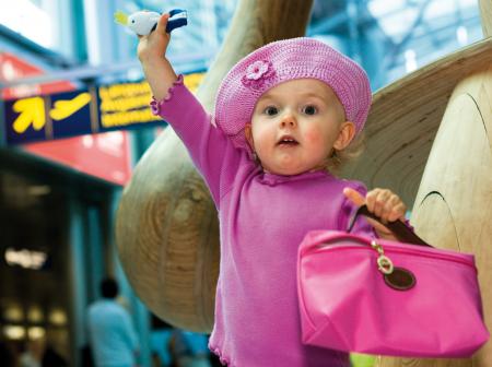 Lapsi pinkeissä vaatteissa lentokentällä.