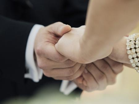 Close up of brides and grooms hand holding.