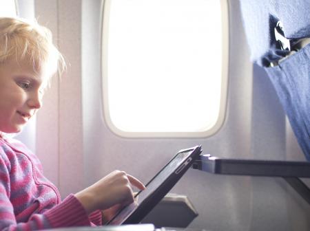 Young child using a tablet on a flight.