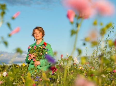 Emma Salokoski kukkaniityllä käsissään kukkakimppu.