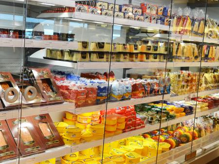 Fish fillets and cheeses in cold food display fridge.