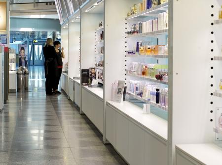 Ihmiset katselevat kosmetiikkatuotteita duty free kaupassa.
