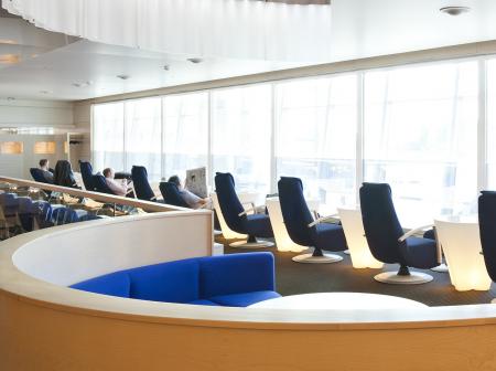 A modern lounge with seats and large windows.