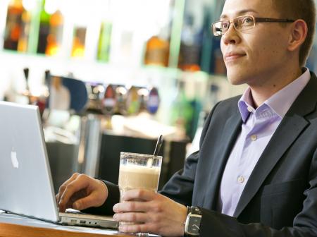 A man using laptop in a cafe.