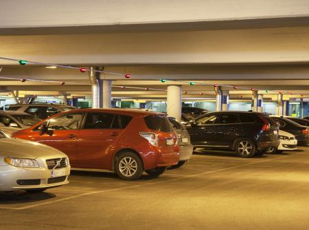 Multiple of cars parked in a lit parking hall.