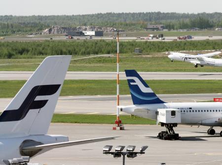 A view of Helsinki Airport runway with multiple airplanes.