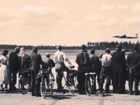 People in row watching aeroplaning taking off.