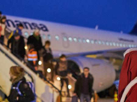Santa watching as people are leaving a plane.