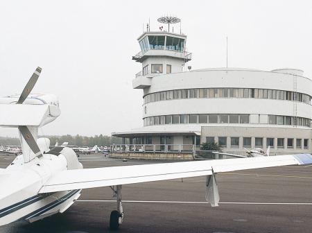 Small aircrafts and a flight control tower at Malmi airport.