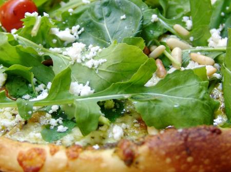 Pizza with fresh arugula and pine nuts.