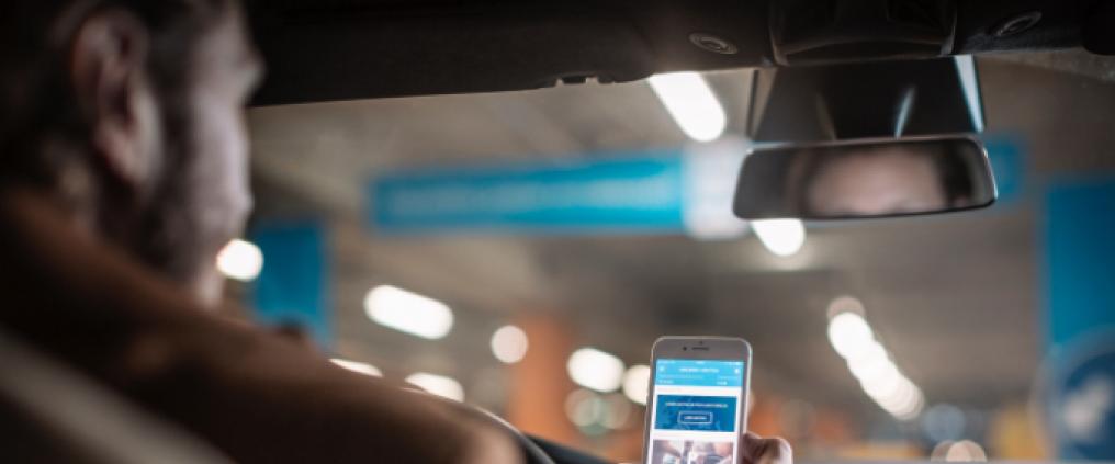 Man sitting in the car and watching his mobile phone