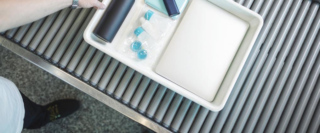 Liquid products and electronics on a security control tray.