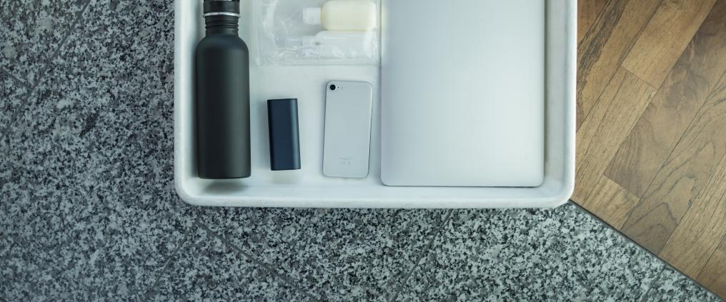 Liquid products and electronics on a security control tray.