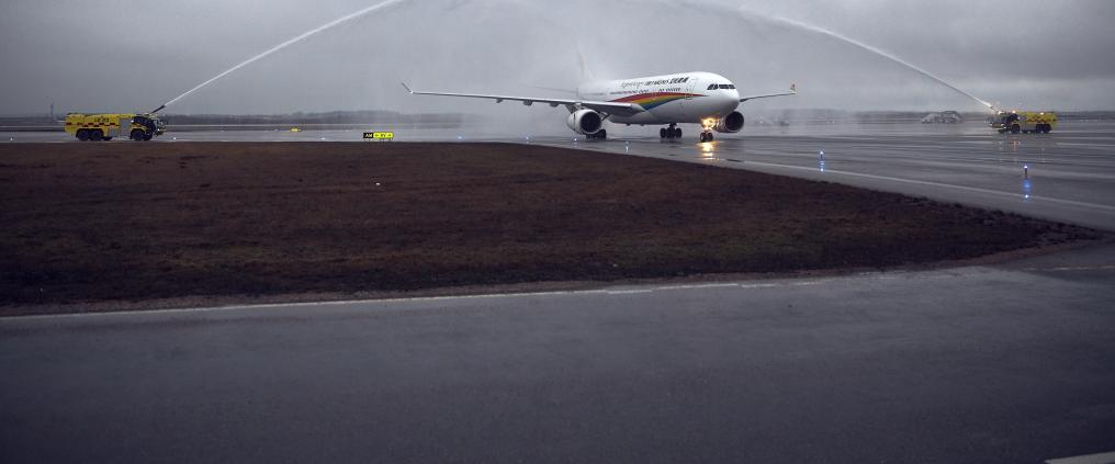 Airplane is receiving a water salute on a cloudy day.