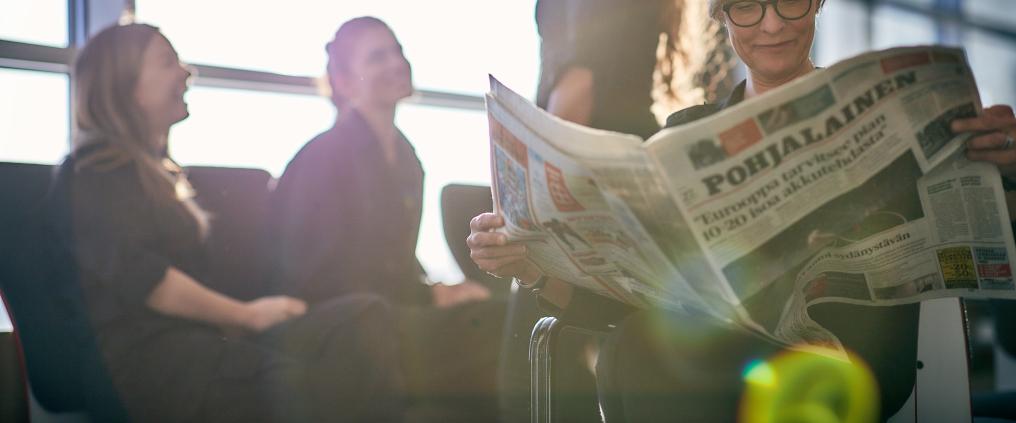 Matkustaja lukee lehteä Vaasan lentoasemalla. 