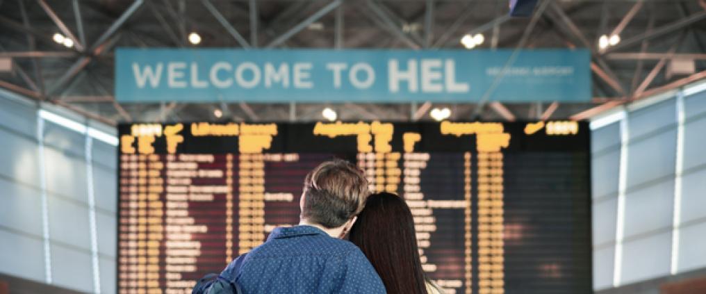 A couple in front of the big screen at Helsinki Airport
