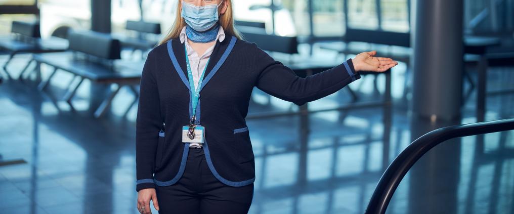 Finavian henkilökunta ohjeistaa matkustajia kädellä maski naamassa