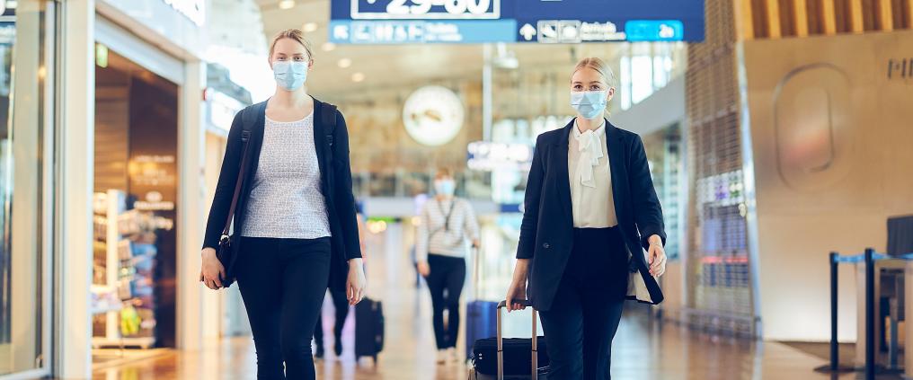 Kaksi matkustajaa kävelee reippaasti terminaalissa maskit kasvoilla