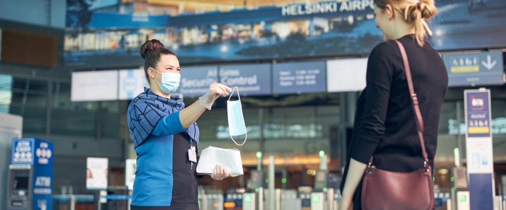 A passenger service person gives a mask for a passengers