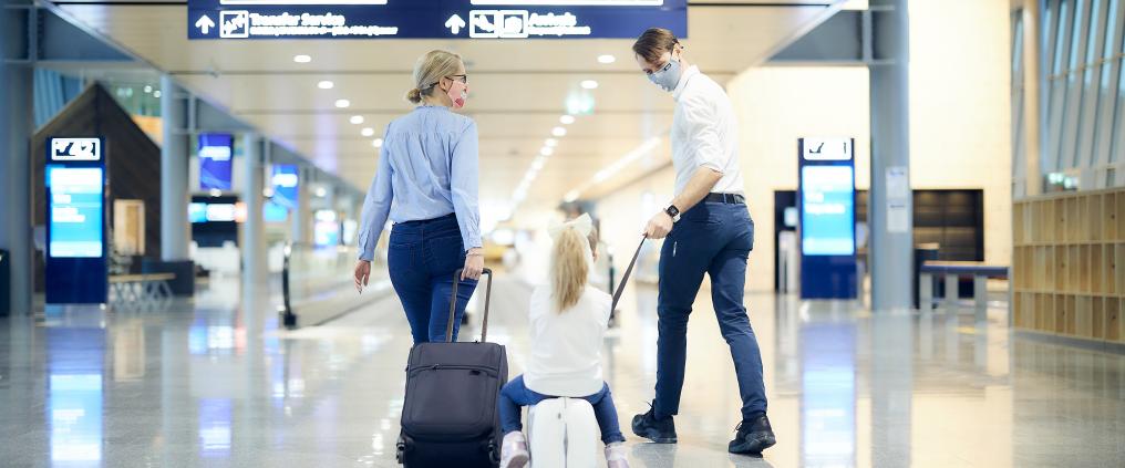 Kolmihenkinen ryhmä kävelee pitkää käytävää pitkin.