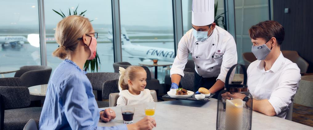 Perhe ruokailee Helsinki-Vantaan lentoasemalla.