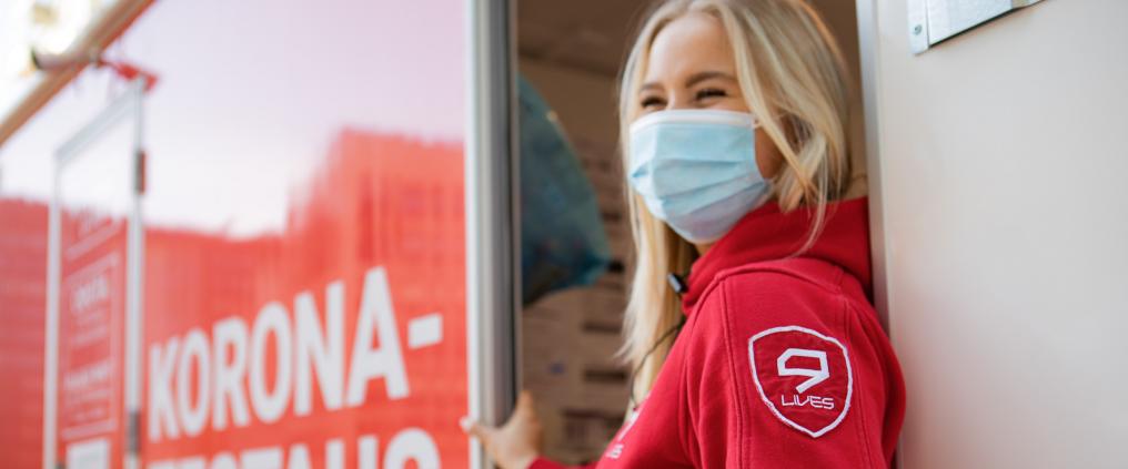 Punapukuinen 9Livesin työntekijä koronatestauspisteen ovella