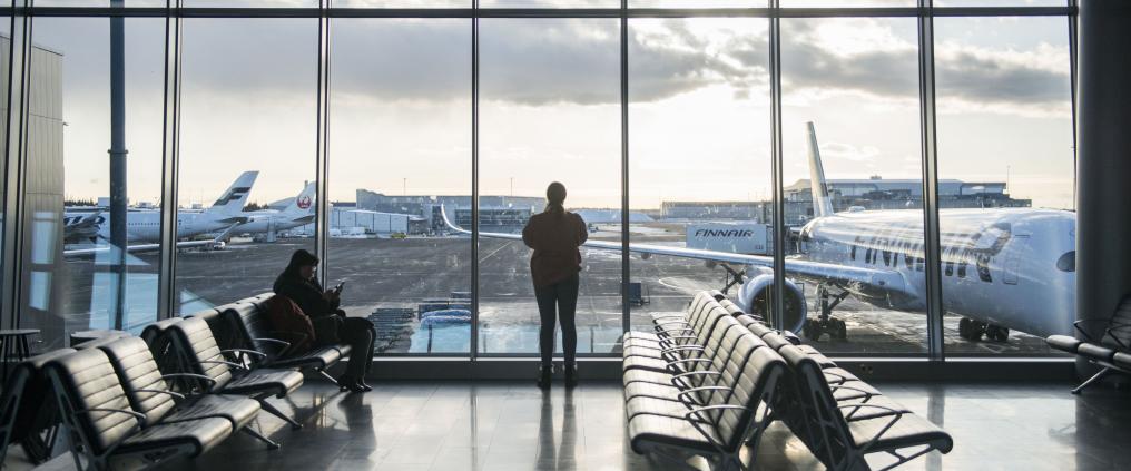 Iso lasiseinä, jonka edessä seisoo ihminen. Takana näkyy lentokoneita.