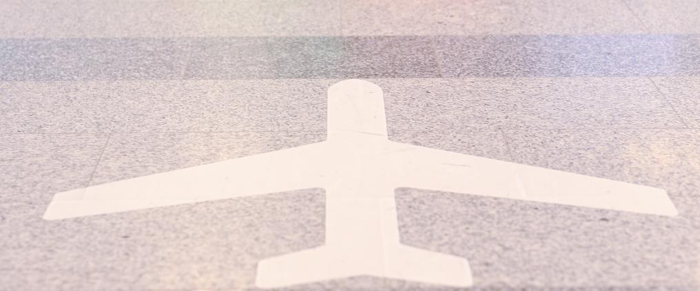 Lentokoneen muotoinen opastarra kivilattiassa.