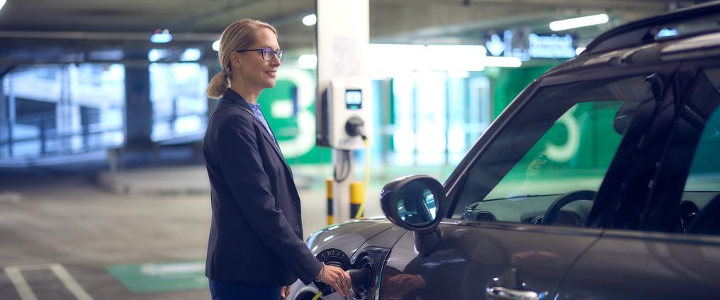 Matkustaja lataa autoaan Helsinki-Vantaan lentoaseman pysäköintihallissa