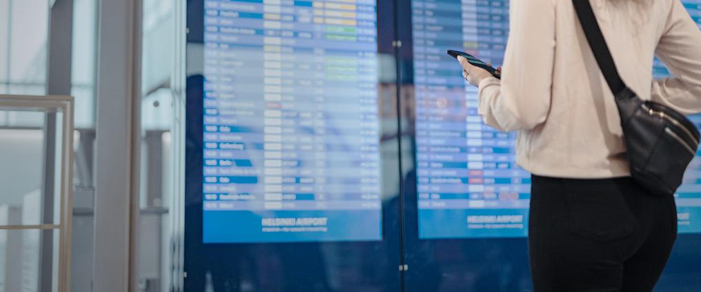 Matkustaja tarkistaa oman lentonsa ajan lentökentän aikataulunäytöltä