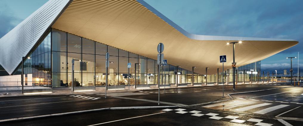 Helsinki-Vantaan lentoaseman terminaali, jossa on lasinen seinä ja puinen lippa sisäänkäynnin yllä.