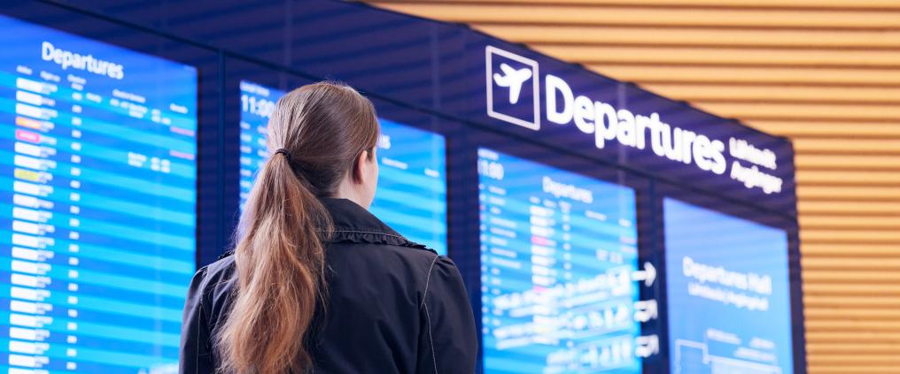 Matkustaja katsoo lentotietonäyttöä lentoasemalla