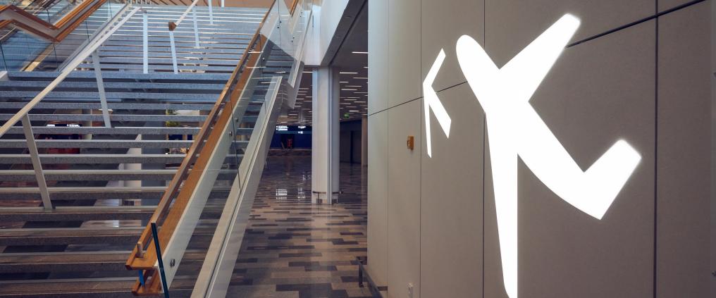 Kuvassa portaat, joissa on puinen kaide ja lentokoneen muotoinen valokyltti.