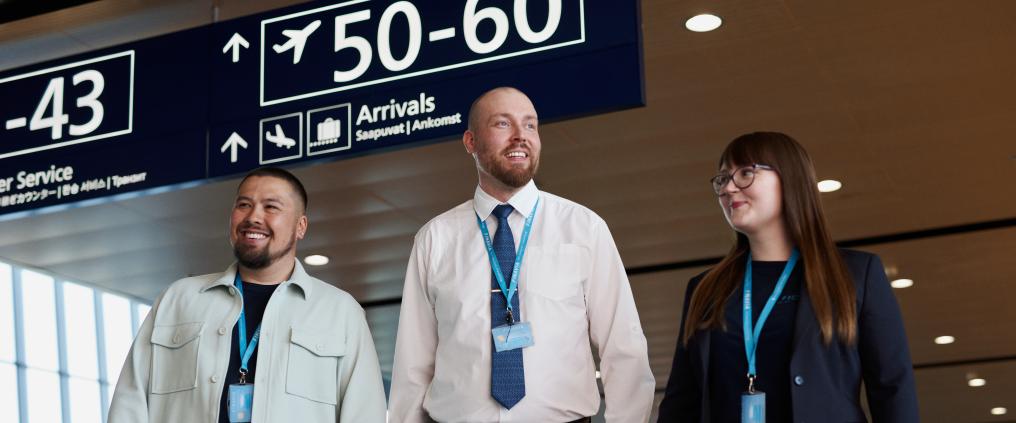 Kolme Finavian työntekijää kävelee kohti kameraa lentoaseman sisätiloissa.