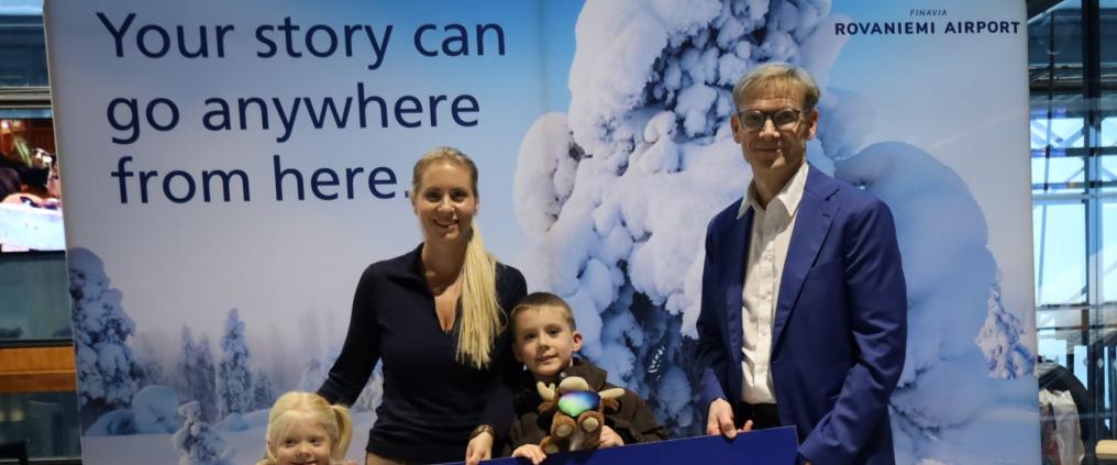 Ryhmäkuva matkustajista ja lentoasemanpäälliköstä ison miljoonas matkustaja -kyltin kanssa.