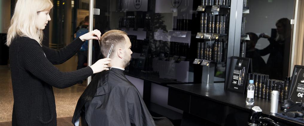 Barber is cutting customer's hair.