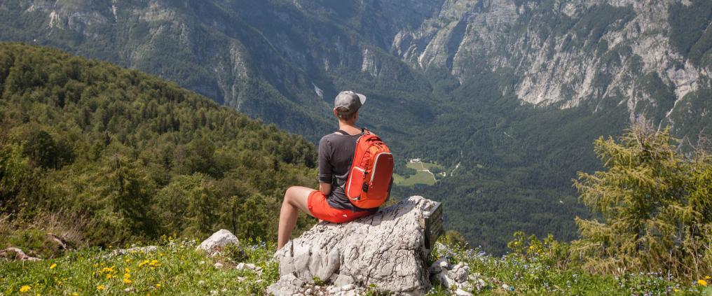 Hiker sitting on a rock and admiring the mountain view.