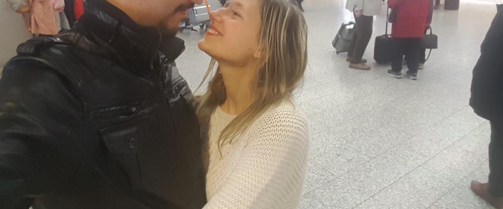 A couple smiling and looking into each others eyes at 2B arrival hall at Helsinki Airport.