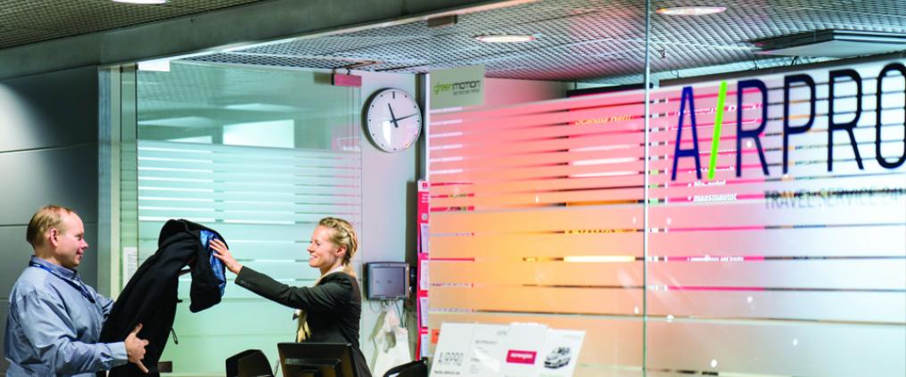 A woman handing a coat to a man.