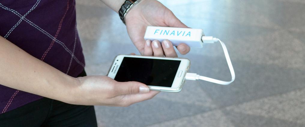 Henkilöllä on kädessään matkapuhelin ja varavirtalähde.