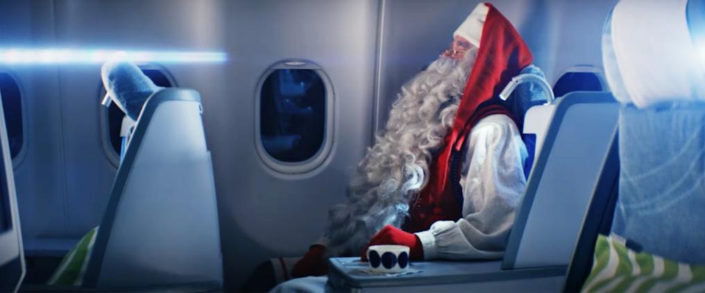 Santa Claus sitting in airplane cabin.