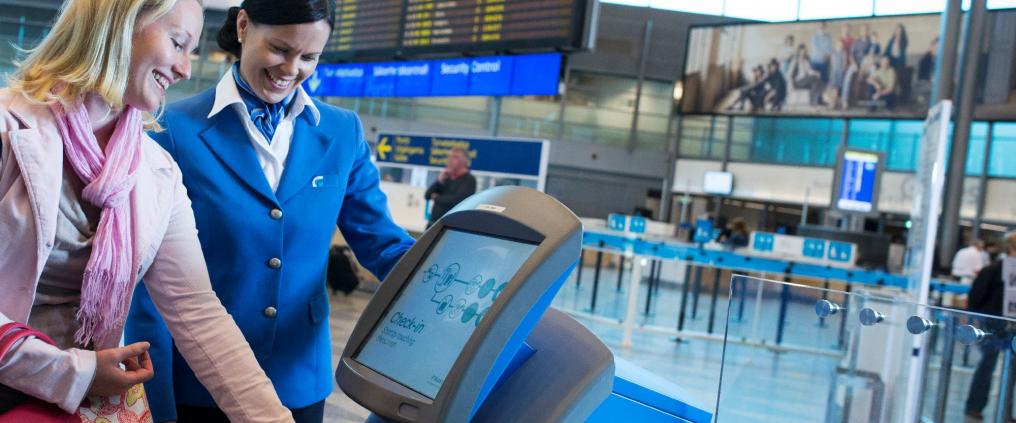 Nainen käyttää lähtöselvitysautomaattia lentokentällä.