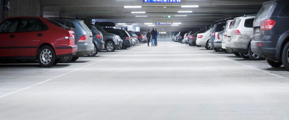 Multiple of cars parked in a lit parking hall.